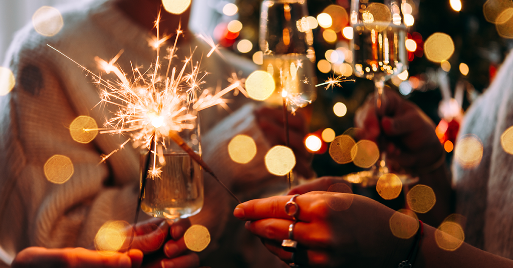 Partygoers holding glasses and sparklers.